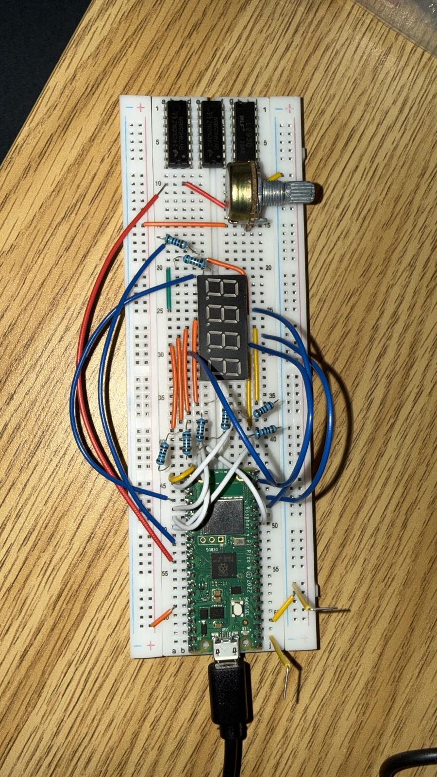 Breadboard with a Raspberry Pi Pico W, a 4-digit 7-segment display, an L293D chip, resistors and a potentiometer